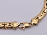 a close up of a gold chain bracelet on a white surface