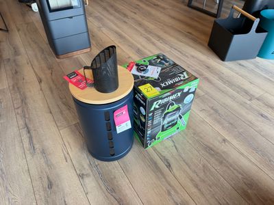 une poubelle noire posée par terre à côté d'un carton