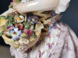 a figurine of a woman holding a basket of flowers