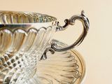 a silver cup and saucer sitting on a saucer