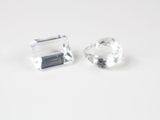 une paire de pierres de quartz transparent facettées posées sur une surface blanche