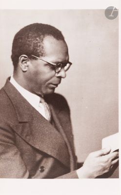 a black and white photo of a man in a suit reading a book