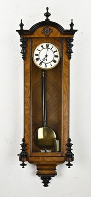 a wooden clock hanging on the wall with a pendulum on it
