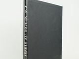 a black book sitting on top of a white table next to a white wall