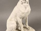 statue of a white dog sitting on a cushion with its mouth open