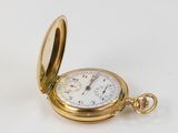 a gold pocket watch sitting on a white surface