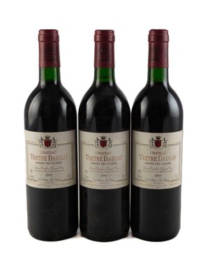 trois bouteilles de vin rouge posées l'une à côté de l'autre sur une surface blanche