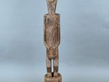 une statue en bois représentant un homme debout sur un socle