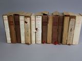 several old books are lined up in a row on a gray surface