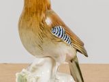 two figurines of birds sitting on top of a wooden table