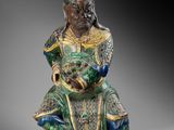a statue of a man sitting on top of a green and blue statue