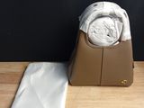 michael korsch watch and bag on a wooden table next to a black wall