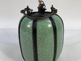 green and black vase with a bamboo stick sticking out of it