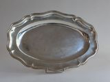 silver plate with scalloped edge on stand on white background