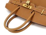 the brown leather handbag has a gold buckle on the handle