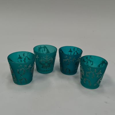 quatre verres bleus ornés de motifs dorés, posés sur une surface blanche