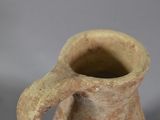 a small brown vase with a handle on a table