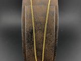 une chaîne en or sur un bracelet marron avec un fond noir