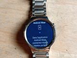 une montre connectée posée sur une table en bois, avec un écran bleu