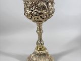une coupe en argent ancien posée sur un socle, sur fond blanc