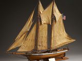 maquette en bois d'un voilier aux voiles beiges, posée sur un socle