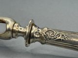 une cuillère en argent avec un manche en métal posée sur une table