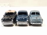 three toy cars are lined up in a row on a white surface