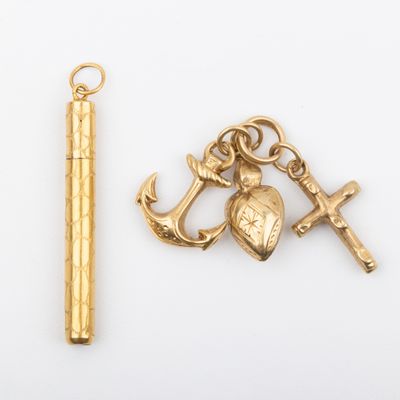 deux breloques en or et un stylo posés sur une surface blanche
