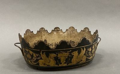 an old black and gold bowl sitting on top of a white table