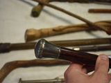 a person holding a wooden stick in front of a bunch of old canes