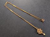Gros plan sur un collier en or orné d'une croix