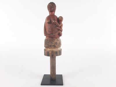 an old wooden statue of a woman holding a baby on top of a table