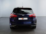the back end of a blue nissan versa parked in a room