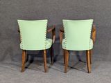 pair of green chairs with studded backrests against a gray background