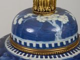 a blue and white vase with a gold top