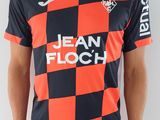 Cet homme porte un t-shirt rouge et noir et un pantalon noir.