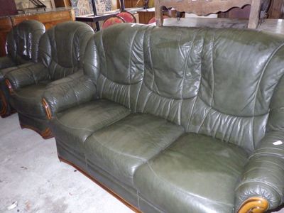 un canapé en cuir vert et deux fauteuils dans une pièce