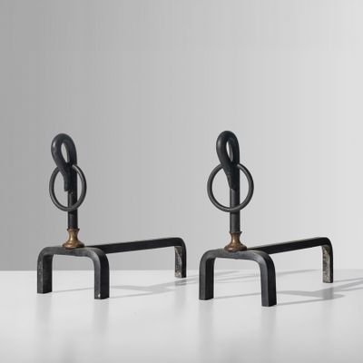 une paire de bougeoirs noirs en fer et en laiton posés sur une table blanche