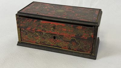 une vieille boîte en bois ornée d'un motif rouge et noir