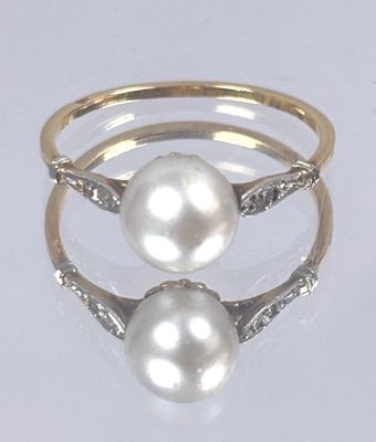 pair of pearl and diamond rings on a white surface