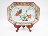 une assiette décorée de fleurs et d'oiseaux, posée sur un socle