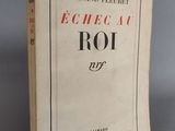 un vieux livre posé sur une table à côté d'un mur gris