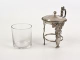 a small silver object next to a glass on a white surface