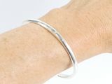 someone is wearing a silver bracelet with a thin band on their arm