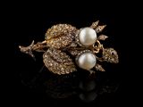 a close up of a pearl and diamond broochle on a black surface