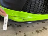 the front bumper of a green sports car with a sticker on it