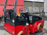 a close up of a red and black road roller parked in a parking lot