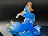 une figurine en verre représentant un homme à cheval sur une vague