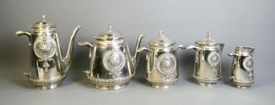 five silver teapots and a coffee pot are lined up on a table