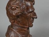 bronze bust of a man with a hat on a gray background